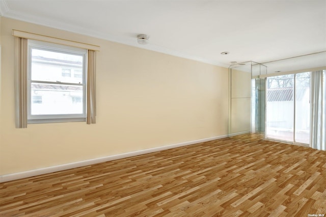 unfurnished room with light wood-style flooring, ornamental molding, plenty of natural light, baseboards, and a smoke detector