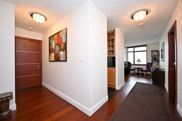 hallway featuring dark wood-type flooring and baseboards