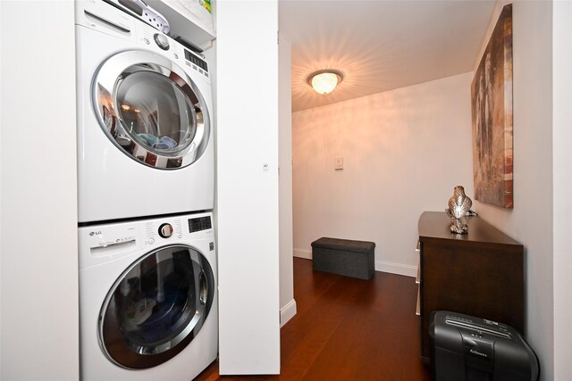 laundry room featuring stacked washer and clothes dryer, dark wood finished floors, and baseboards