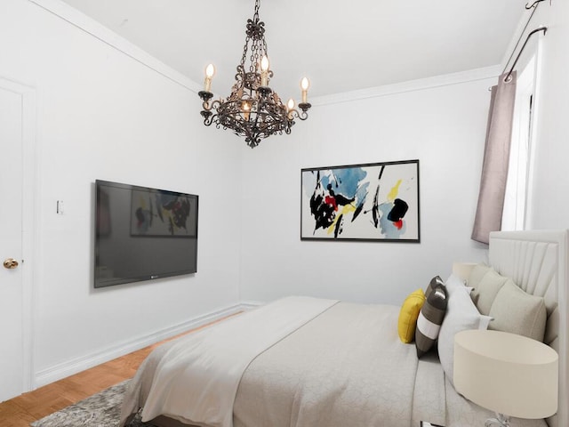 bedroom featuring a chandelier, wood finished floors, and baseboards