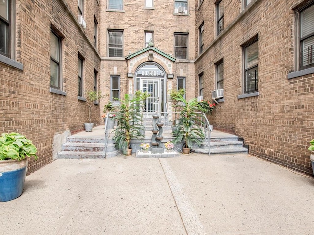 view of exterior entry with brick siding and cooling unit