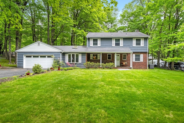 view of front of property with an attached garage, driveway, cooling unit, covered porch, and a front lawn