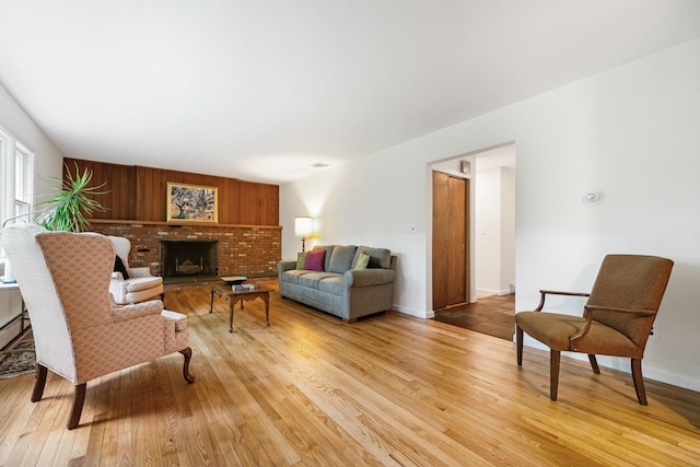 living room featuring light wood-style floors, a brick fireplace, baseboards, and a baseboard heating unit