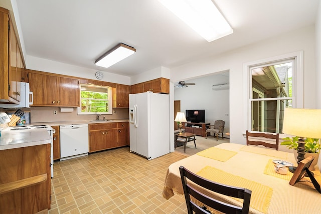 kitchen with white appliances, light countertops, brown cabinetry, brick patterned flooring, and a sink
