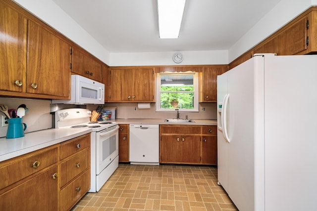 kitchen featuring white appliances, a sink, brown cabinets, and light countertops