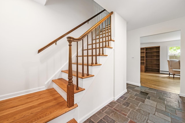 stairs with baseboards, stone tile floors, and a baseboard heating unit