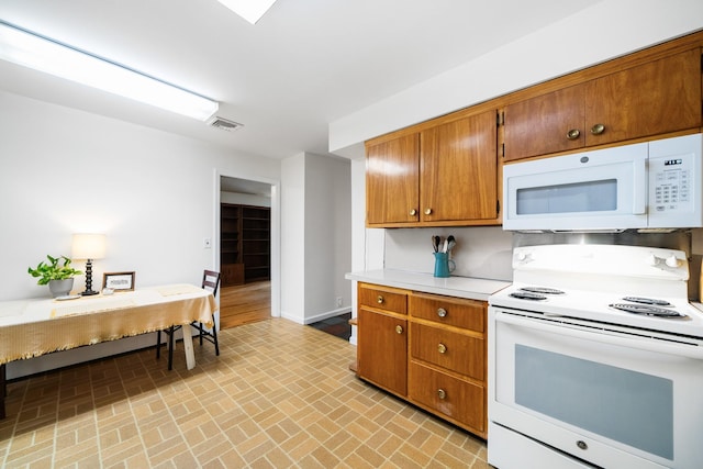 kitchen with white appliances, brick patterned floors, light countertops, brown cabinetry, and baseboards