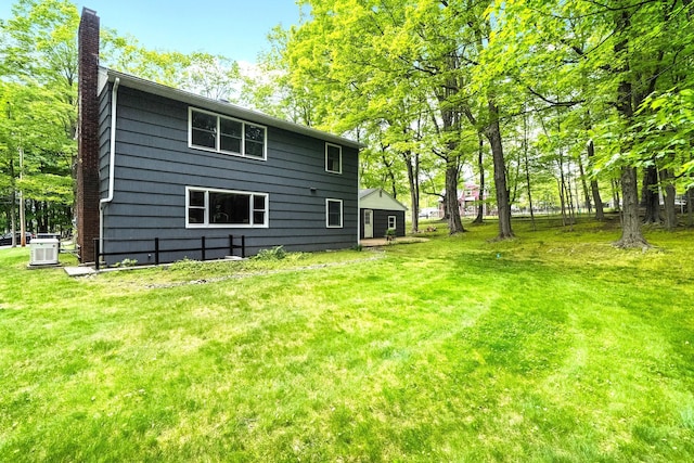 back of house with a chimney, cooling unit, and a yard