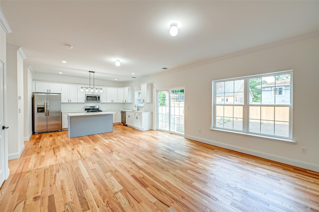 36-A Maple Ave, Port Jefferson Station, NY 11776 - kitchen featuring appliances with stainless steel finishes, ornamental molding, light wood finished floors, white cabinetry, and a center island