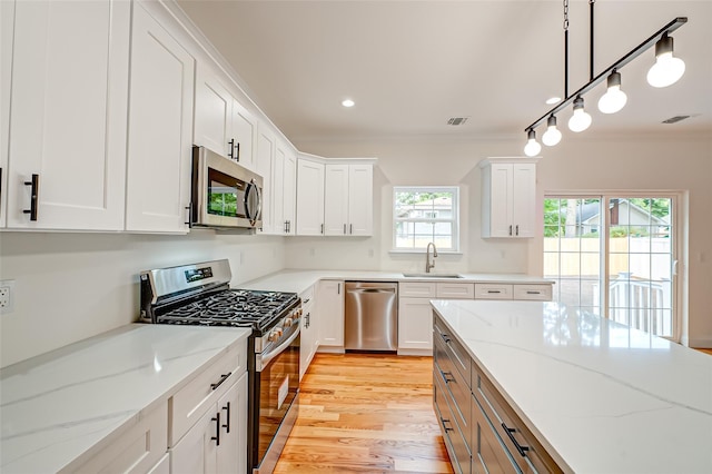36-A Maple Ave, Port Jefferson Station, NY 11776 - kitchen with stainless steel appliances, a sink, ornamental molding, white cabinets, and light wood-style flooring