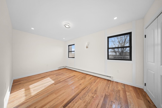 486 Ashford St, Brooklyn, NY 11207 - empty room with a baseboard heating unit, light wood-style flooring, baseboards, and recessed lighting