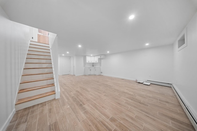 486 Ashford St, Brooklyn, NY 11207 - finished below grade area with a baseboard heating unit, stairway, light wood finished floors, baseboards, and recessed lighting