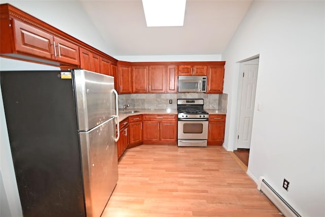 51 Manor Rd, Valley Stream, NY 11580 - kitchen with appliances with stainless steel finishes, a baseboard radiator, lofted ceiling, light wood finished floors, and tasteful backsplash