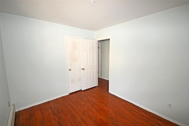 51 Manor Rd, Valley Stream, NY 11580 - unfurnished bedroom featuring a baseboard heating unit, wood finished floors, and baseboards