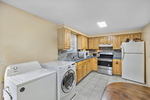 kitchen featuring white appliances, under cabinet range hood, washing machine and dryer, decorative backsplash, and light tile patterned floors