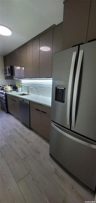 kitchen with stainless steel appliances, modern cabinets, light countertops, light wood-style floors, and tasteful backsplash