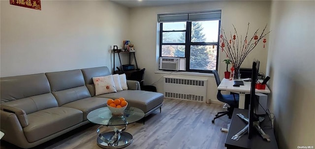 living area with radiator heating unit, wood finished floors, cooling unit, and an office area