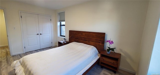 bedroom with wood finished floors, a closet, and baseboards