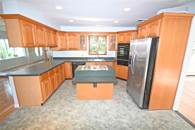 kitchen with black appliances, plenty of natural light, a sink, dark countertops, and recessed lighting