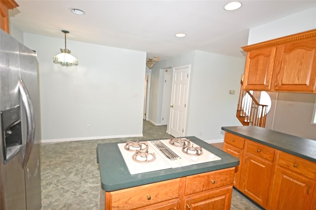 kitchen with stainless steel fridge, dark countertops, recessed lighting, stovetop with downdraft, and decorative light fixtures