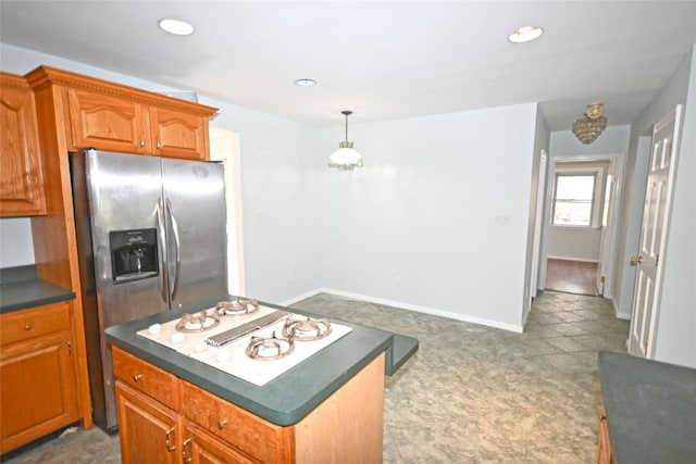kitchen with stovetop with downdraft, dark countertops, brown cabinets, a center island, and recessed lighting
