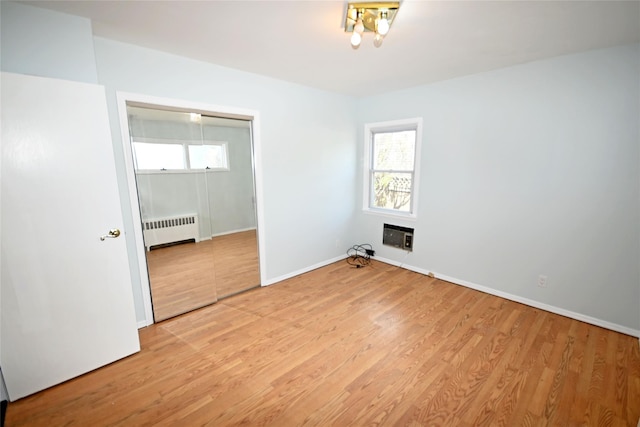 unfurnished bedroom with radiator, light wood-type flooring, and baseboards