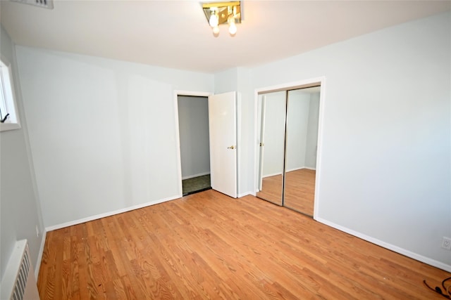 unfurnished bedroom featuring wood finished floors, baseboards, and a closet
