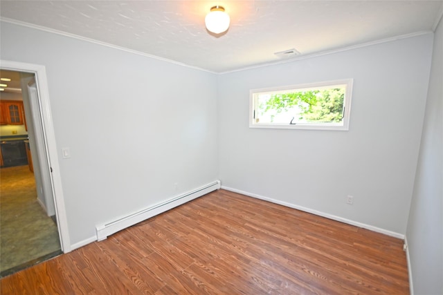 unfurnished room with a baseboard heating unit, wood finished floors, crown molding, and baseboards