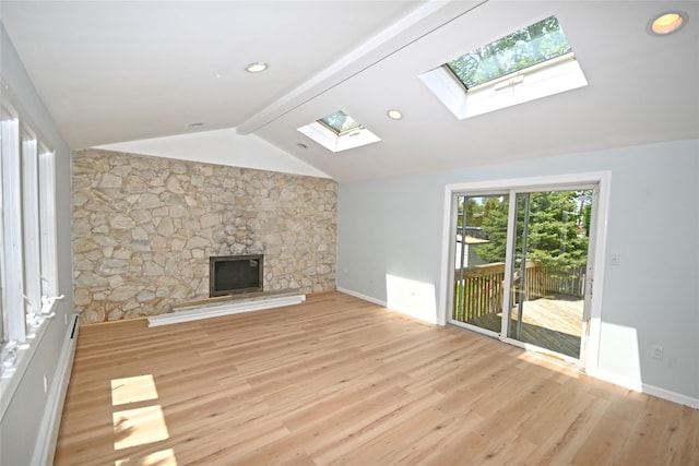 unfurnished living room with a skylight, light wood finished floors, a fireplace, baseboards, and a baseboard heating unit