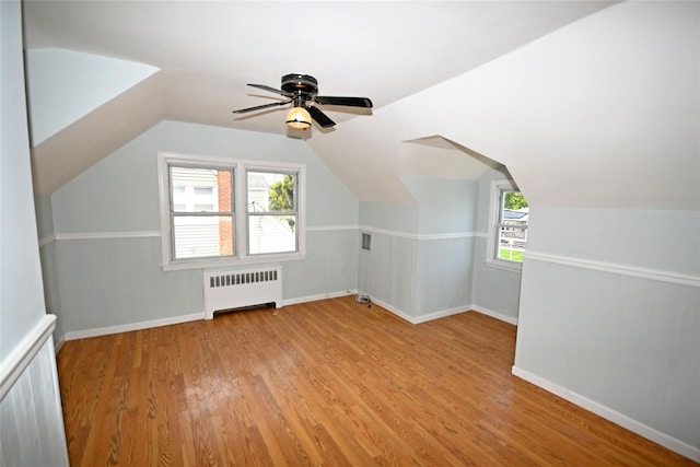 bonus room with radiator, light wood-style flooring, baseboards, and lofted ceiling