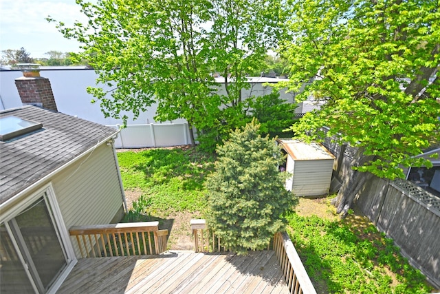 wooden deck with a shed, an outbuilding, and a fenced backyard