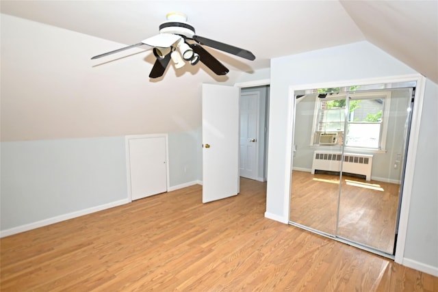 additional living space with radiator heating unit, light wood finished floors, lofted ceiling, cooling unit, and baseboards