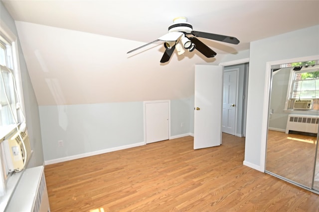additional living space featuring radiator heating unit, light wood-style floors, a ceiling fan, baseboards, and lofted ceiling