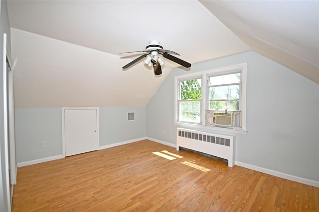 additional living space featuring radiator heating unit, light wood-style floors, baseboards, ceiling fan, and lofted ceiling