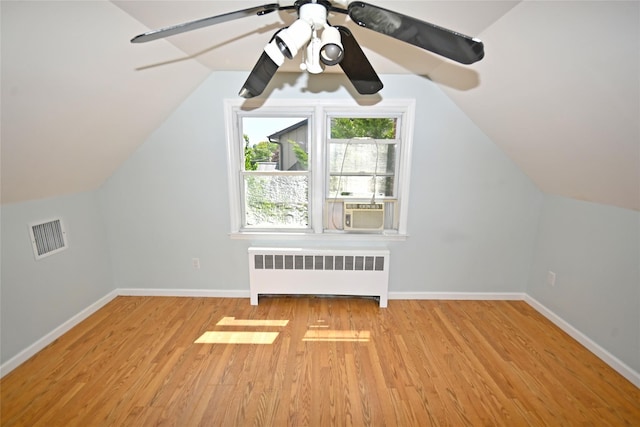 additional living space with radiator heating unit, wood finished floors, baseboards, lofted ceiling, and cooling unit