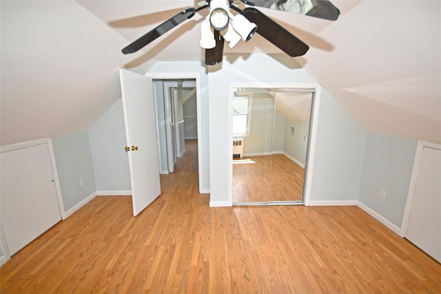 additional living space with light wood-type flooring, baseboards, vaulted ceiling, and radiator heating unit