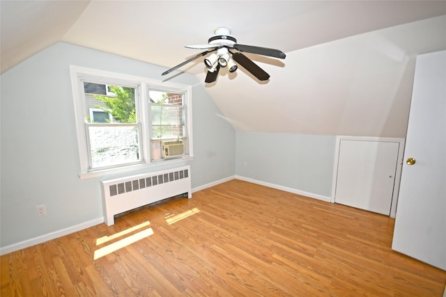 bonus room with radiator heating unit, lofted ceiling, ceiling fan, baseboards, and light wood-type flooring