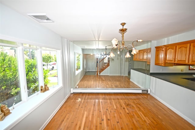 unfurnished dining area featuring a baseboard radiator, a chandelier, light wood-style flooring, baseboards, and stairway