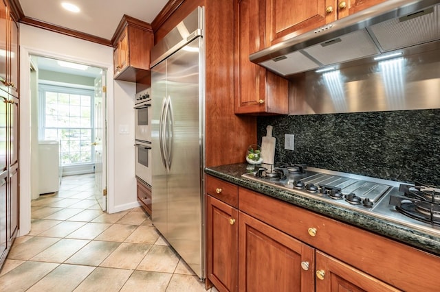 16 Cayuga Rd, Scarsdale, NY 10583 - kitchen with stainless steel appliances, under cabinet range hood, decorative backsplash, light tile patterned flooring, and brown cabinetry