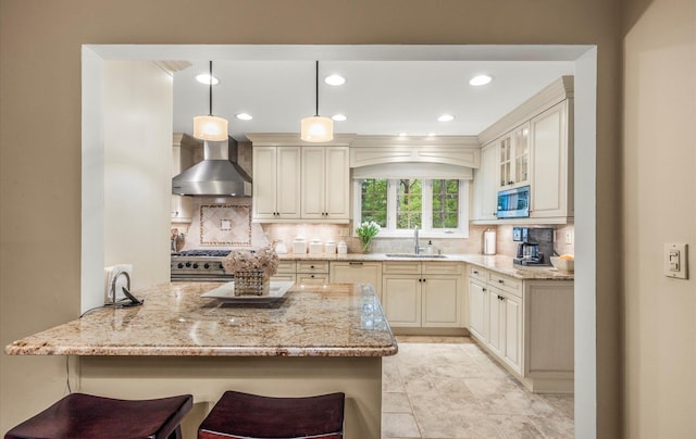 90 Gannet Dr, Commack, NY 11725 - kitchen featuring wall chimney exhaust hood, a sink, light stone counters, a kitchen breakfast bar, and decorative backsplash