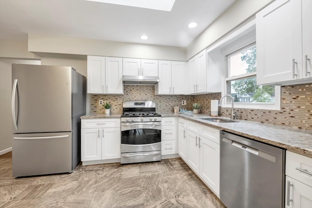 76 Melrose Ave, Lynbrook, NY 11563 - kitchen featuring appliances with stainless steel finishes, a sink, under cabinet range hood, light stone counters, and white cabinets