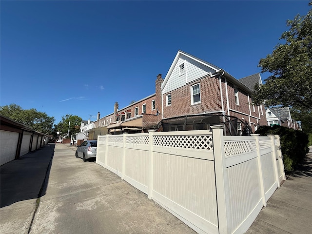 83-46 Penelope Ave, Middle Village, NY 11379 - view of property exterior featuring fence, brick siding, a residential view, and a chimney