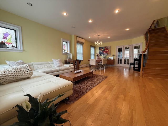 83-46 Penelope Ave, Middle Village, NY 11379 - living room featuring a baseboard heating unit, a chandelier, stairs, light wood finished floors, and french doors