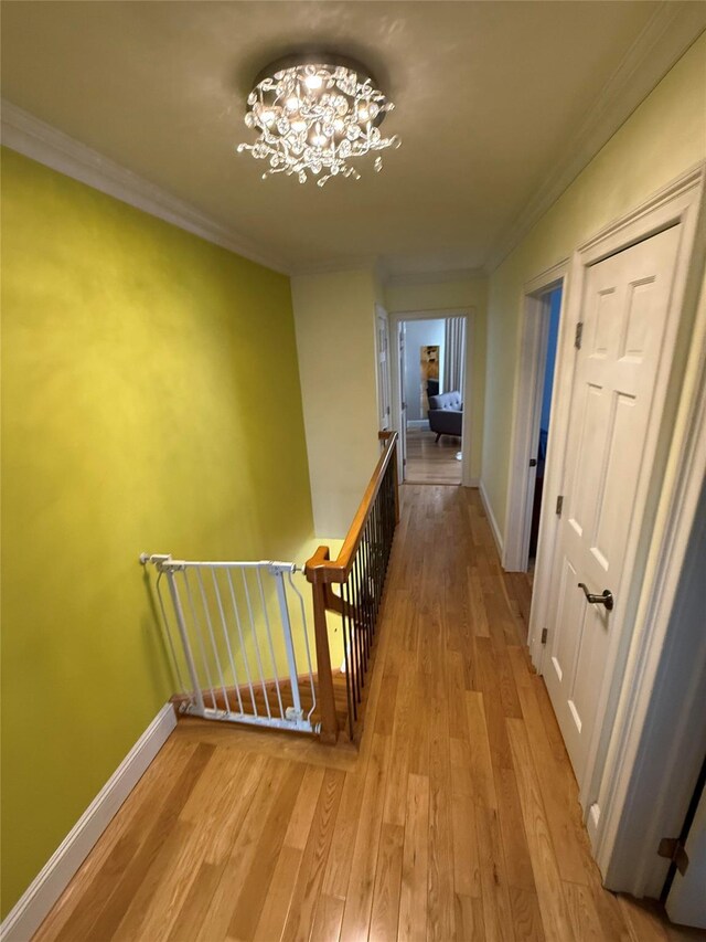 83-46 Penelope Ave, Middle Village, NY 11379 - corridor featuring an upstairs landing, a chandelier, light wood-style floors, ornamental molding, and baseboards
