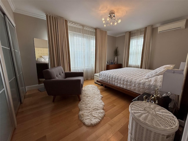 83-46 Penelope Ave, Middle Village, NY 11379 - bedroom with an AC wall unit, crown molding, light wood-type flooring, a chandelier, and baseboards
