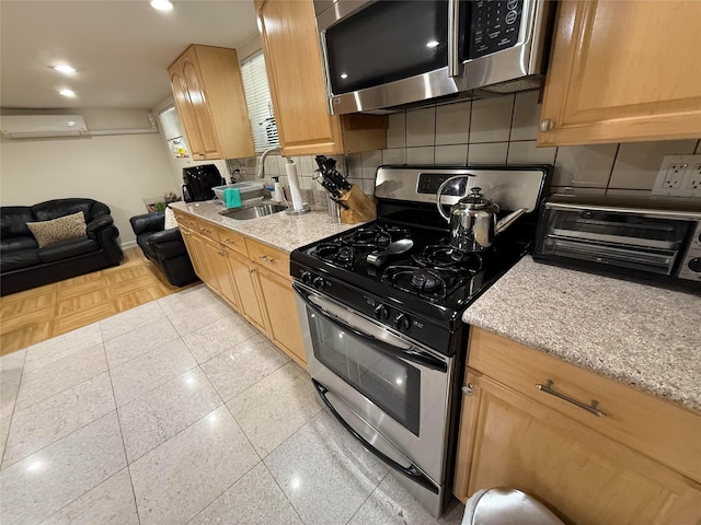 83-46 Penelope Ave, Middle Village, NY 11379 - kitchen featuring stainless steel appliances, tasteful backsplash, a wall unit AC, a sink, and light stone countertops