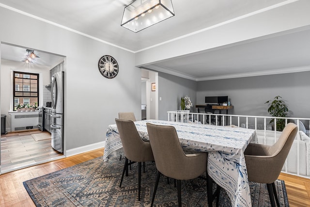 dining room featuring radiator heating unit, ornamental molding, light wood finished floors, and baseboards