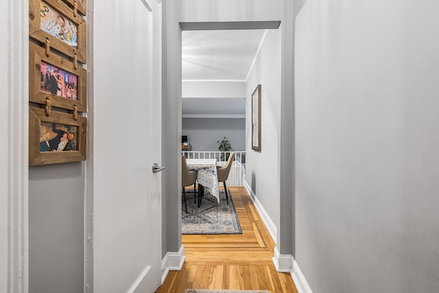 hallway with wood finished floors, crown molding, and baseboards