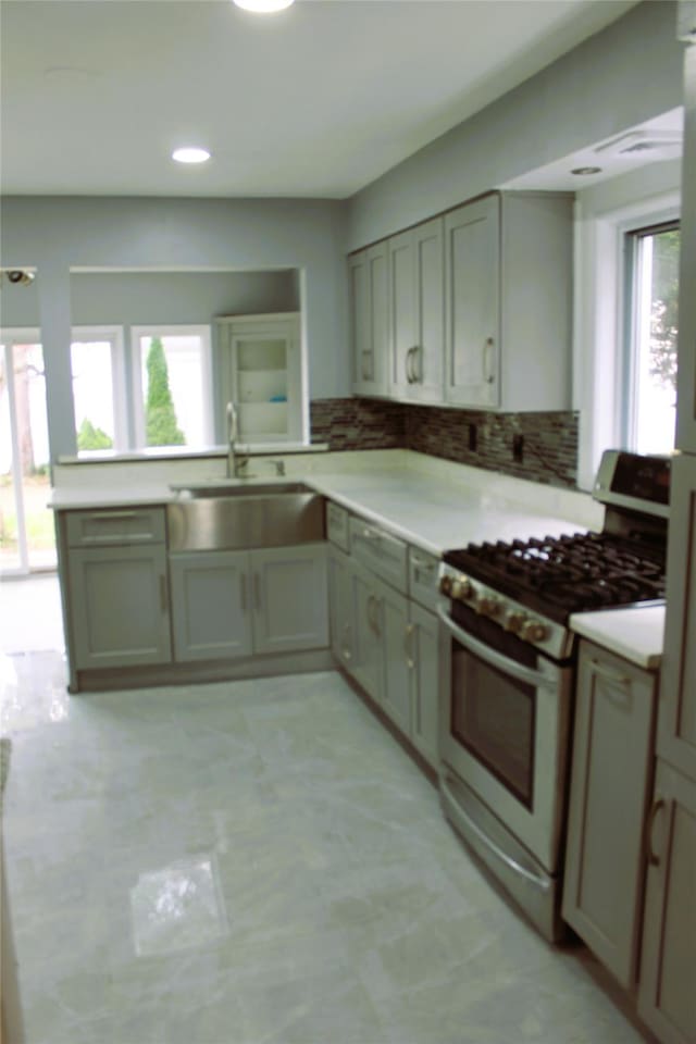 1535 Mattison St, Baldwin, NY 11510 - kitchen featuring stainless steel gas stove, a sink, light countertops, decorative backsplash, and recessed lighting