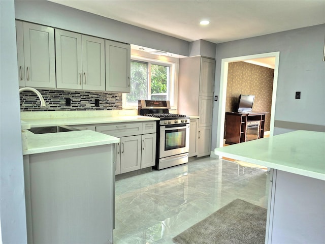 1535 Mattison St, Baldwin, NY 11510 - kitchen with gas stove, light marble finish flooring, backsplash, recessed lighting, and gray cabinetry